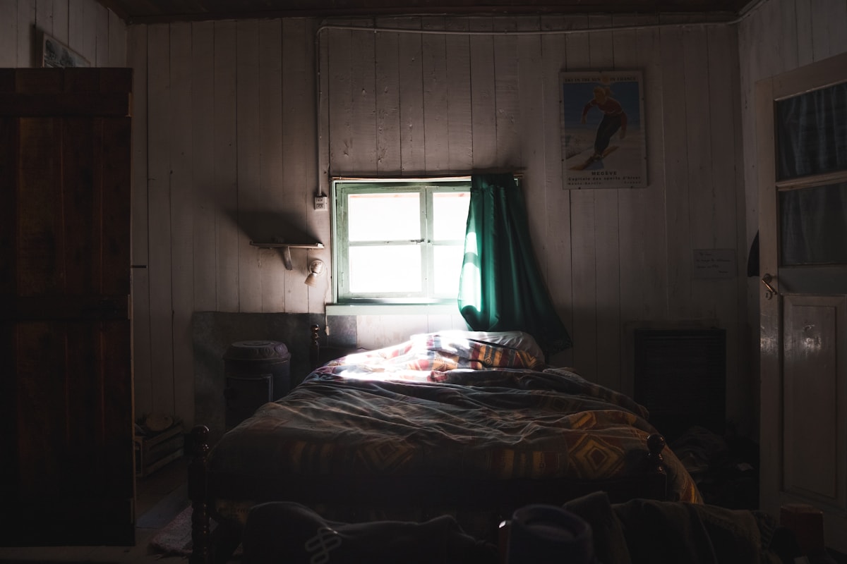 candlelit four-poster bed with linen drapes and a worn wool throw